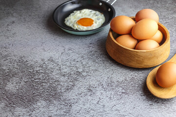 Fried eggs in a pan and fresh eggs on the table