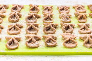 Homemade raw farfalle pasta on cutting board close up. Pasta of whole grain flour sprinkled with flour. Home cooking, healthy food concept