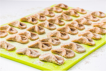 Homemade raw farfalle pasta on cutting board close up. Pasta of whole grain flour sprinkled with flour. Home cooking, healthy food concept