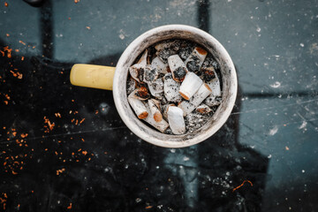 Ashtray, coffee cup as an ashtray filled with cigarette butts, photographed from above, focus on...