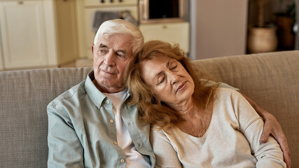Senior european couple resting on sofa at home