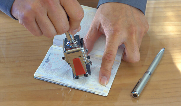 Hand holding a stamp and stamping a passport 
