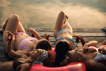 Group of female friends enjoying a summer day laying on the pier at the lake.