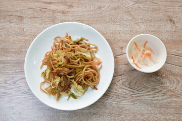 fried yakisoba Japanese noodles slice pork and cabbage with carrot topping dry fish on plate 