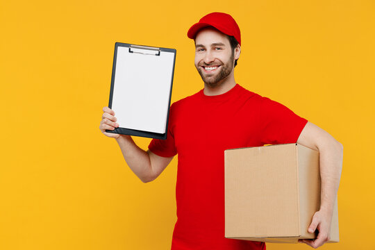 Professional happy delivery guy employee man in red cap T-shirt uniform workwear work as dealer courier hold clipboard with papers document box isolated on plain yellow background. Service concept