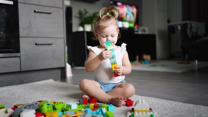 Caucasian child a little girl is playing in the constructor at home. Educational toys for children.