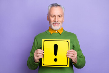 Photo of cheerful retired man wear green sweater showing caution banner isolated violet color background