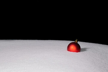 one red Christmas ball is lying on the snow