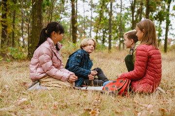 Multiracial four teenagers talking and smiling in autumn forest