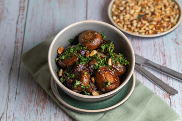 Plate of fried mushrooms with dill, garlic, pine nuts and parsley.