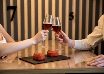 Оn Valentine's day couple drinking red wine with red heart cakes