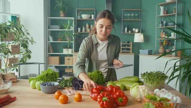 Young Woman Makes a Diet Plan of Correct Nutrition Using a Tablet in the Kitchen, Using a Calorie Counter in a Weight Loss App. Nutrition and Dietetics. Healthy Food and Technology Concept.