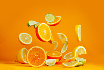 Oranges, lemons and limes cut into slices. Citrus vegetables fly on an orange background. Preparing vegetables for juice and cocktails.