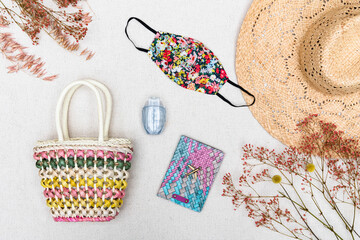 Obraz premium Flat lay of Coronavirus face mask covering with essential summer holiday travel items for a vacation in the Covid-19 pandemic