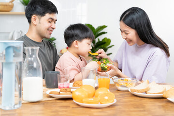 Happy refreshment family breakfast in morning, asian young parent father, mother and little cute boy, child having meal in kitchen eating together at home. Cheerful, enjoy cooking people.