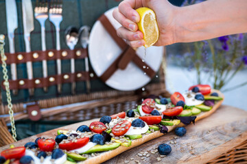 Stylish summer picnic set up, with a picnic hamper and vegetarian baguette of avocado, tomatoes and mozarella cheese