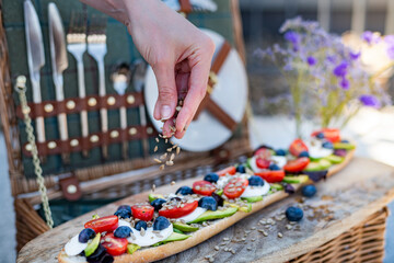 Stylish summer picnic set up, with a picnic hamper and vegetarian baguette of avocado, tomatoes and mozarella cheese