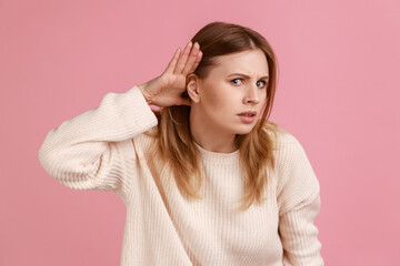 Portrait of blond woman holding hand near ear and listening carefully, having hearing problems,...