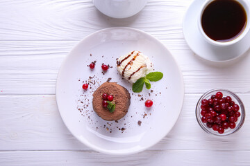 Chocolate fondant with ice cream, cranberries and mint on a white plate