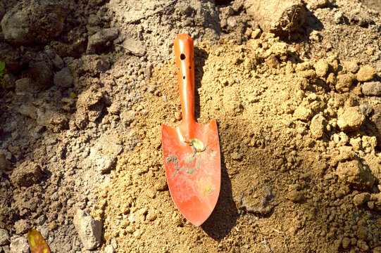 Orange hoe placed on a pile of soil. Concept. Agricultural tools.
