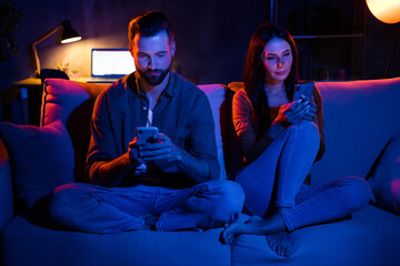 Naklejka na ściany i meble Photo of spouses friends lady guy sit cozy divan use smart app search website sale in late dark apartment flat