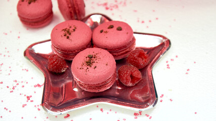 French raspberry macaroons on a plate in the form of a star. Juicy ripe raspberries in the form of a decoration