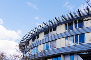 Rounded facade of a modern building with sun protection in Augsburg under blue sky