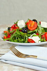 Greek salad in a white bowl. Fresh vegetable salad on a white background. Food on a shabby table. Bowl on an old wooden board.