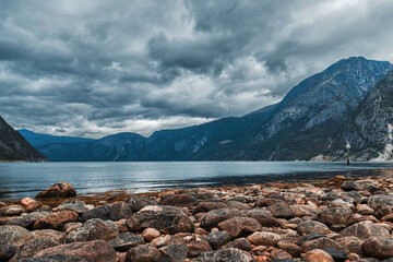 steinige Küste mit Bergen und dunklen Wolken