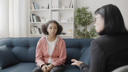 Therapist talking to sad teen girl during counselling session, mental health