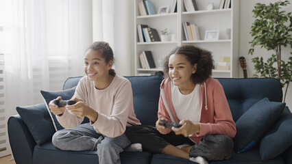 Teenage girls playing videogame at home, competition between siblings, fun