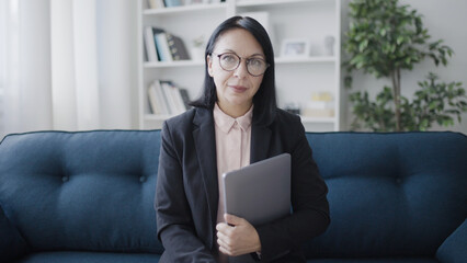 Qualified psychologist in eyeglasses looking at camera, holding laptop, teacher