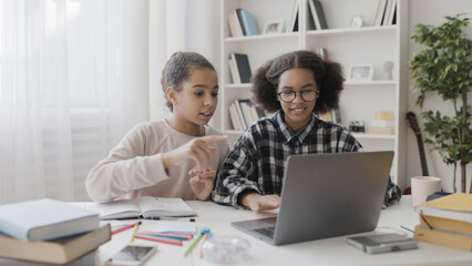 Fototapeta na wymiar African American teenager helping best friend to do online homework on laptop