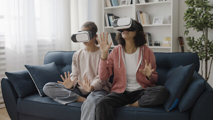 Obraz premium Surprised African American girls trying on virtual reality simulator, 3d world experience