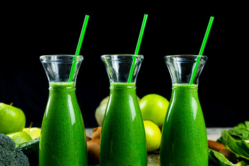 Healthy green smoothies with spinach, apple, kiwi, broccoli and mint in glass jar with fruits and vegetables on the wooden table. Detox and healthy concept