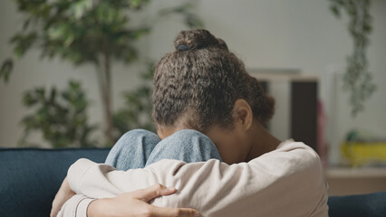 Unhappy black girl sitting on sofa, teenager depressed by bullying problem