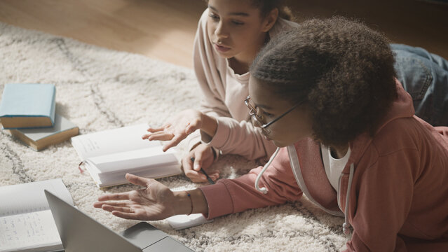 School students studying home, surfing internet on laptop, discussing math problem