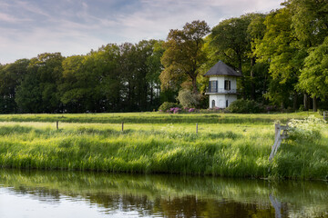 Fototapeta premium A small white tower in the middle of a meadow along a ditch in the Netherlands