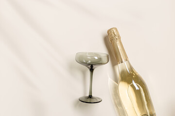 Champagne glasses tinted grey glass, Champagne or sparkling wine bottle on beige background....