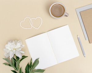 Flat lay, top view office table desk. Workspace with blank copybook, pen, cup of coffee, white peony flower