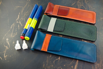 Leather insulin pen cases different colors for people with diabetes. Genuine leather craft. Flat lay.