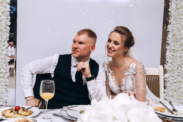 The bride and groom in the banquet hall are receiving congratulations. Newlyweds at the wedding table.