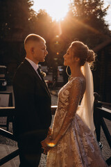 Walk the newlyweds at sunset. The bride and groom in the rays. Evening landscape.