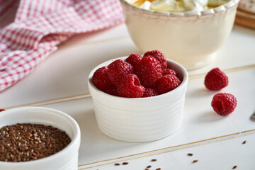 A bowl of fresh raspberries with cottage cheese and flax seed oil in the background. Budwig diet.