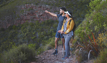 The view from this trail is spectacular. Shot of a young couple enjoying the sunset view while out on a hike on a mountain range.