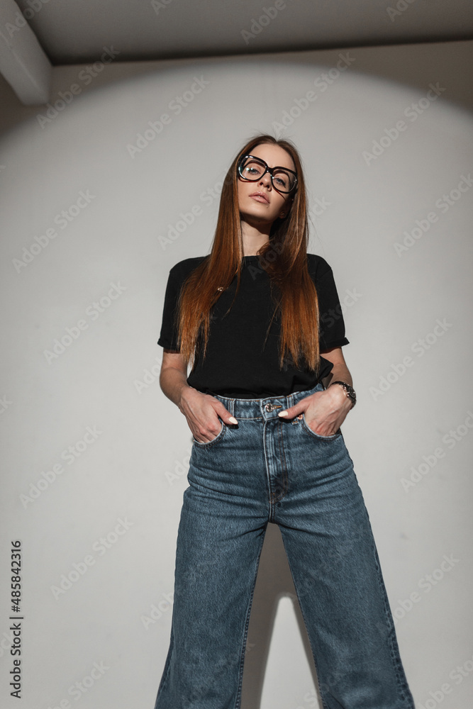 Wall mural pretty cool stylish girl with vintage eyewear glasses in black fashion t-shirt and wide leg jeans po