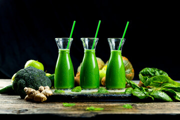 Healthy green smoothies with spinach, apple, kiwi, broccoli and mint in glass jar with fruits and vegetables on the wooden table. Detox, diet, healthy, vegetarian drink concept
