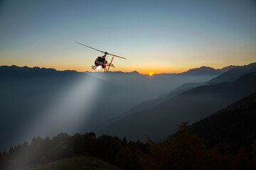 helicopter with lighthouse in night flight in the high mountains - 485842779