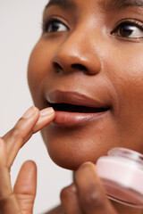 Close-up of woman applying lip balm - obrazy, fototapety, plakaty
