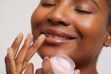 Close-up of smiling woman applying lip balm - obrazy, fototapety, plakaty